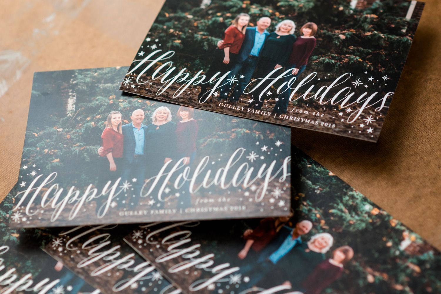 Stack of holiday greeting cards with script text on dark background.