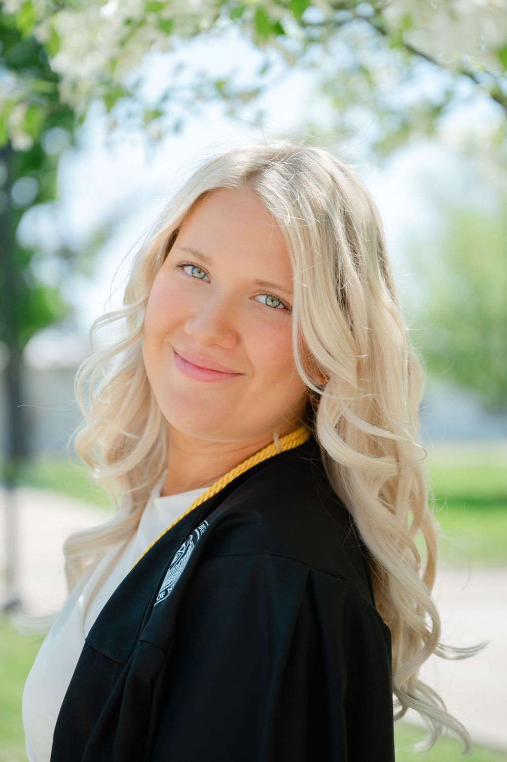 Portrait of a graduate in black robes smiling outdoors.