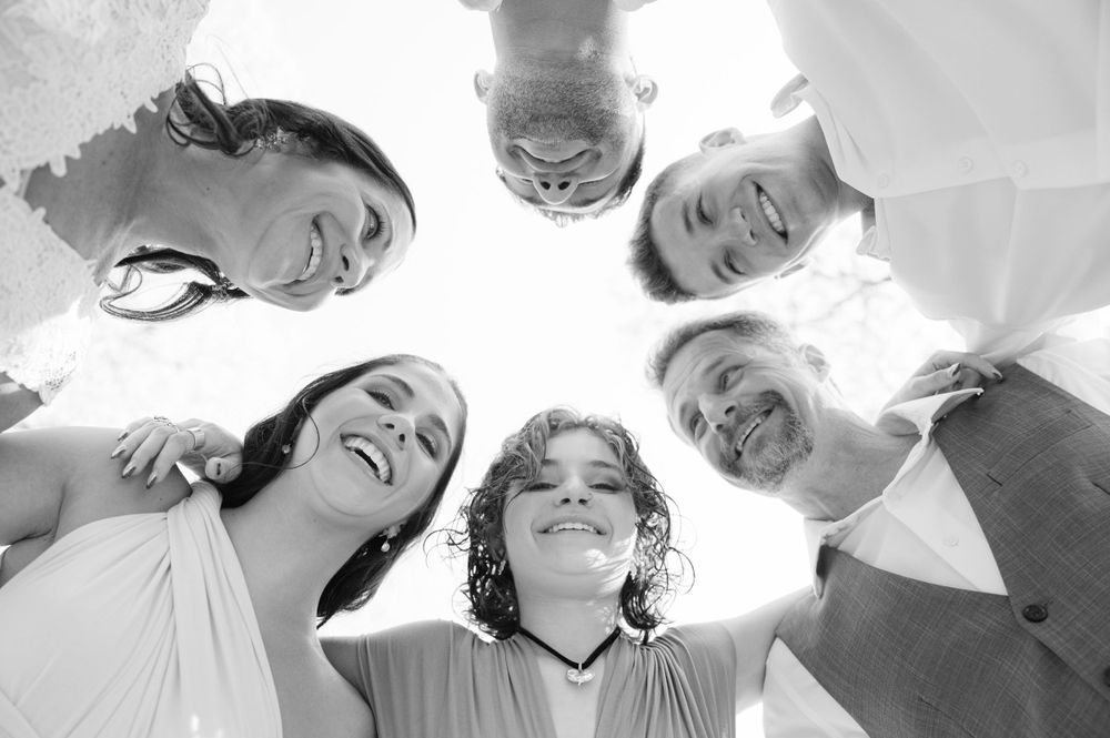 Group of friends forming a circle looking down at the camera with bright smiles.