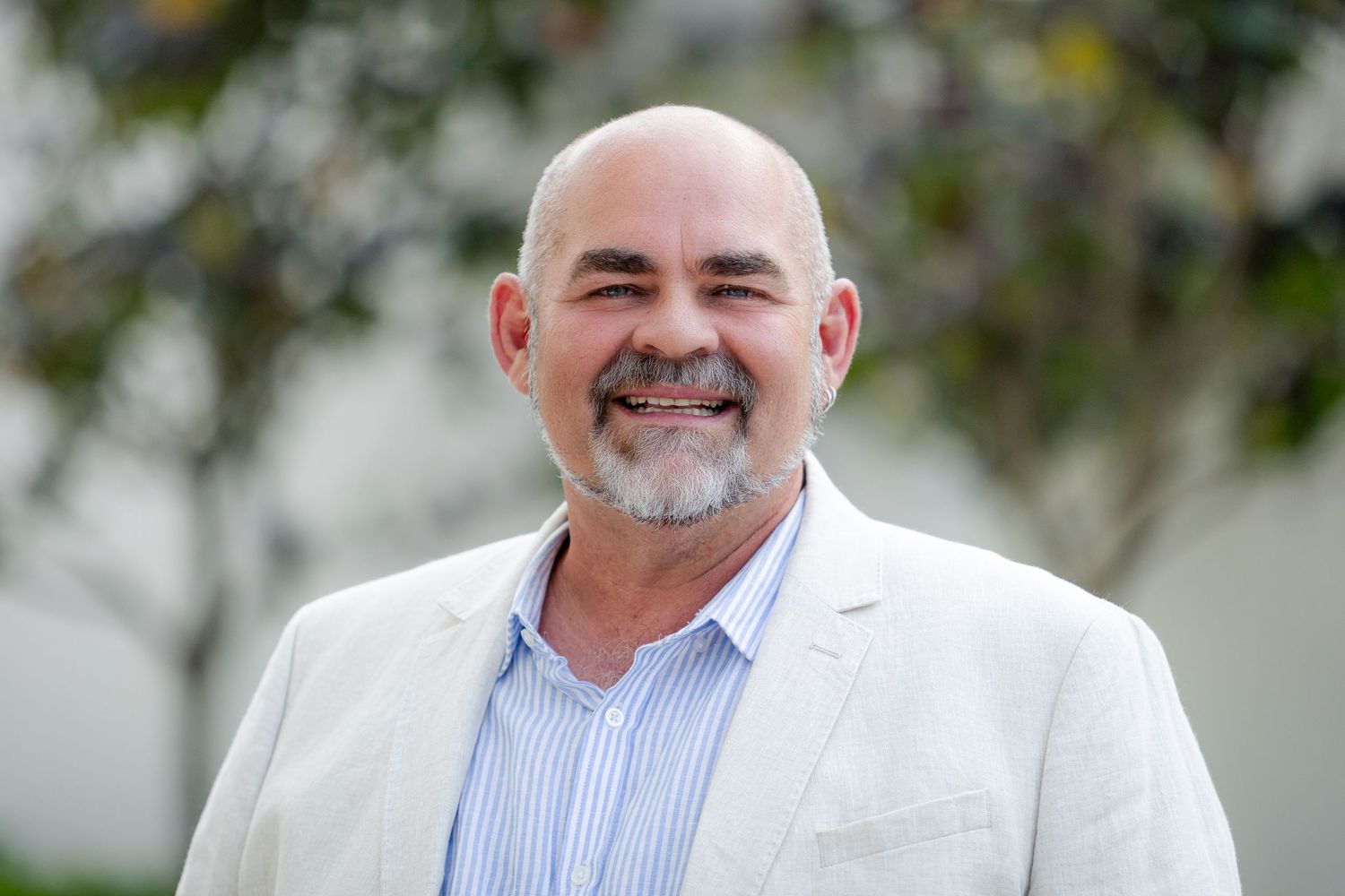 Professional outdoor portrait of a person in white jacket and striped shirt.