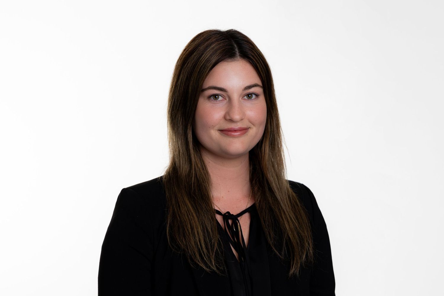 Studio portrait of someone with long dark hair wearing a black top against white background.