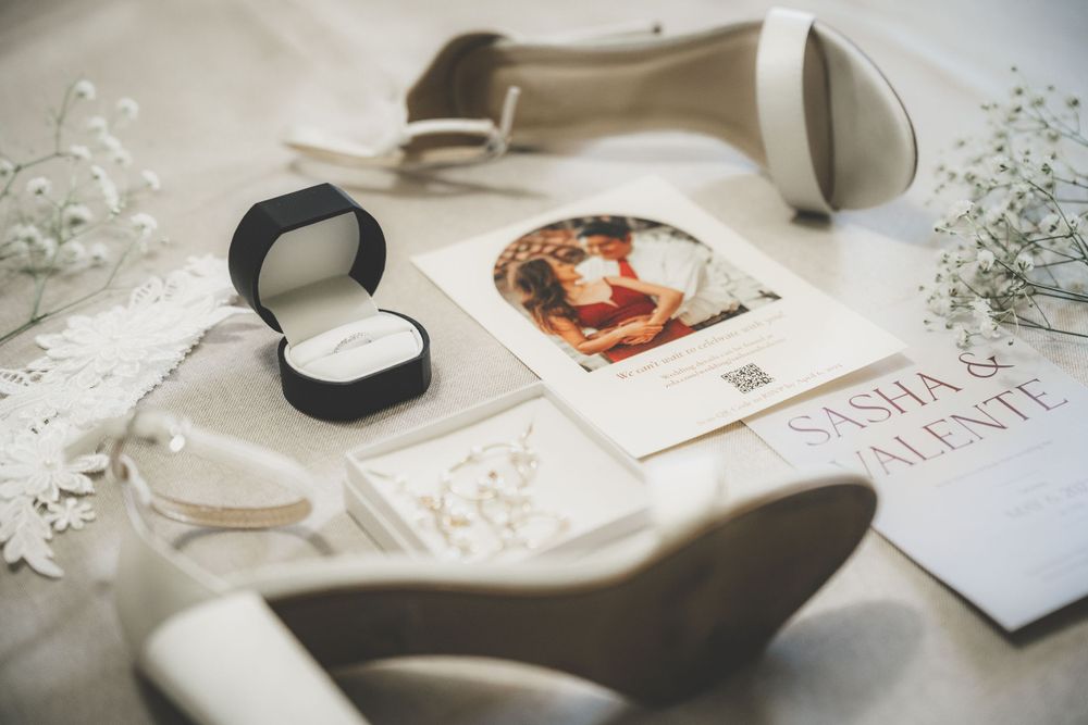 Wedding flat lay featuring bridal heels, engagement ring, and Sasha and Valente invitation.