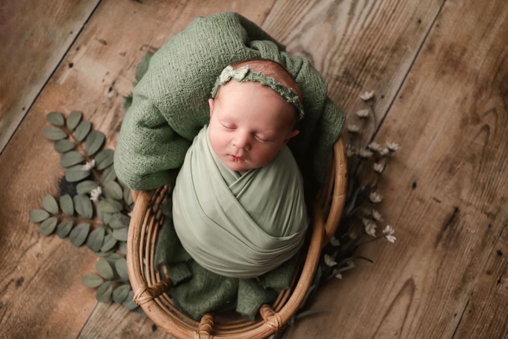 posed newborn portrait, studio baby girl in wood basket prop with flowers