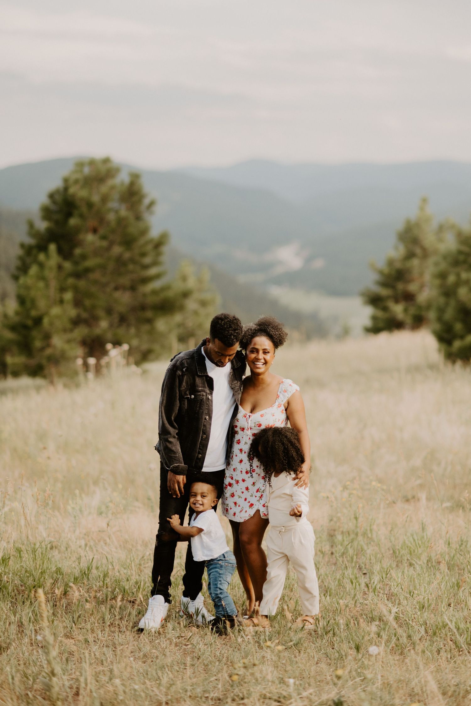 A family stands candidly for the camera in front of the colorado mountains