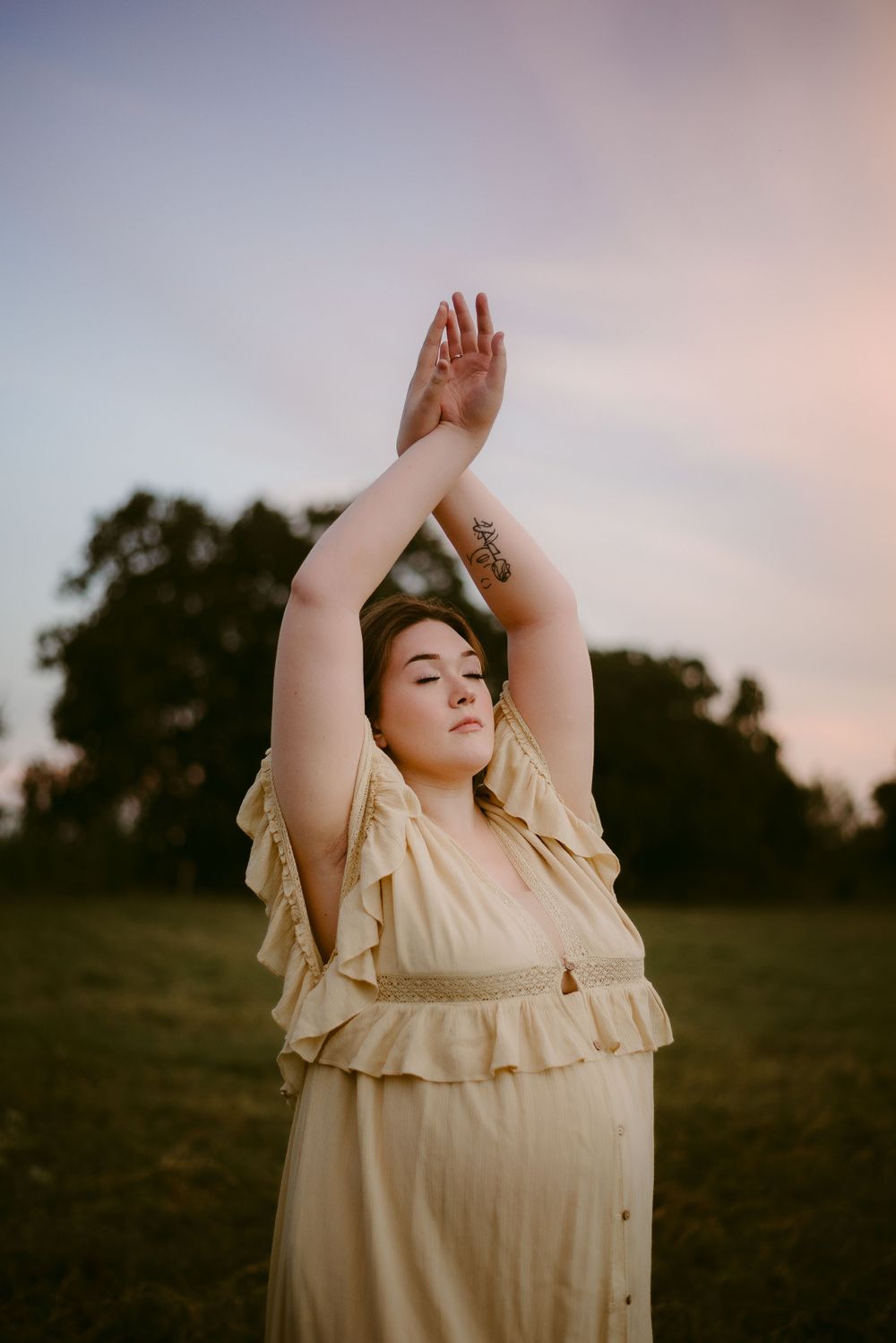 A Pregnant Mother with her hands above her wearing a Free People Gown at Sunset in Seguin, Texas
