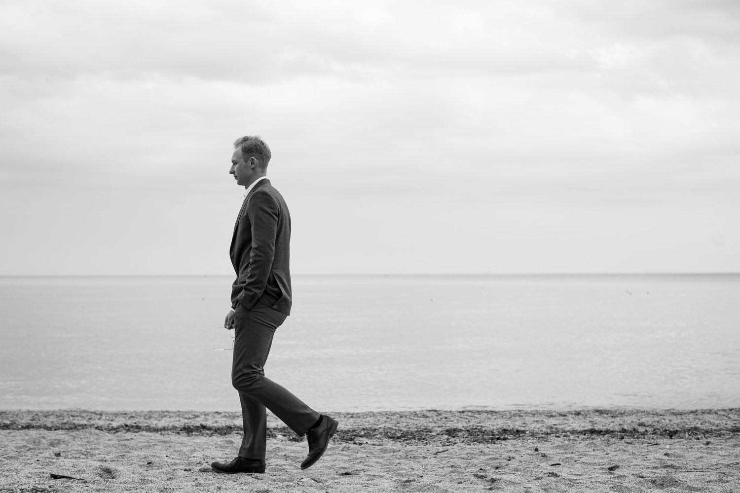 Black and white photo of person walking alone on Edgewater Huntington Cleveland Ohio beach shoreline photo session branding.
