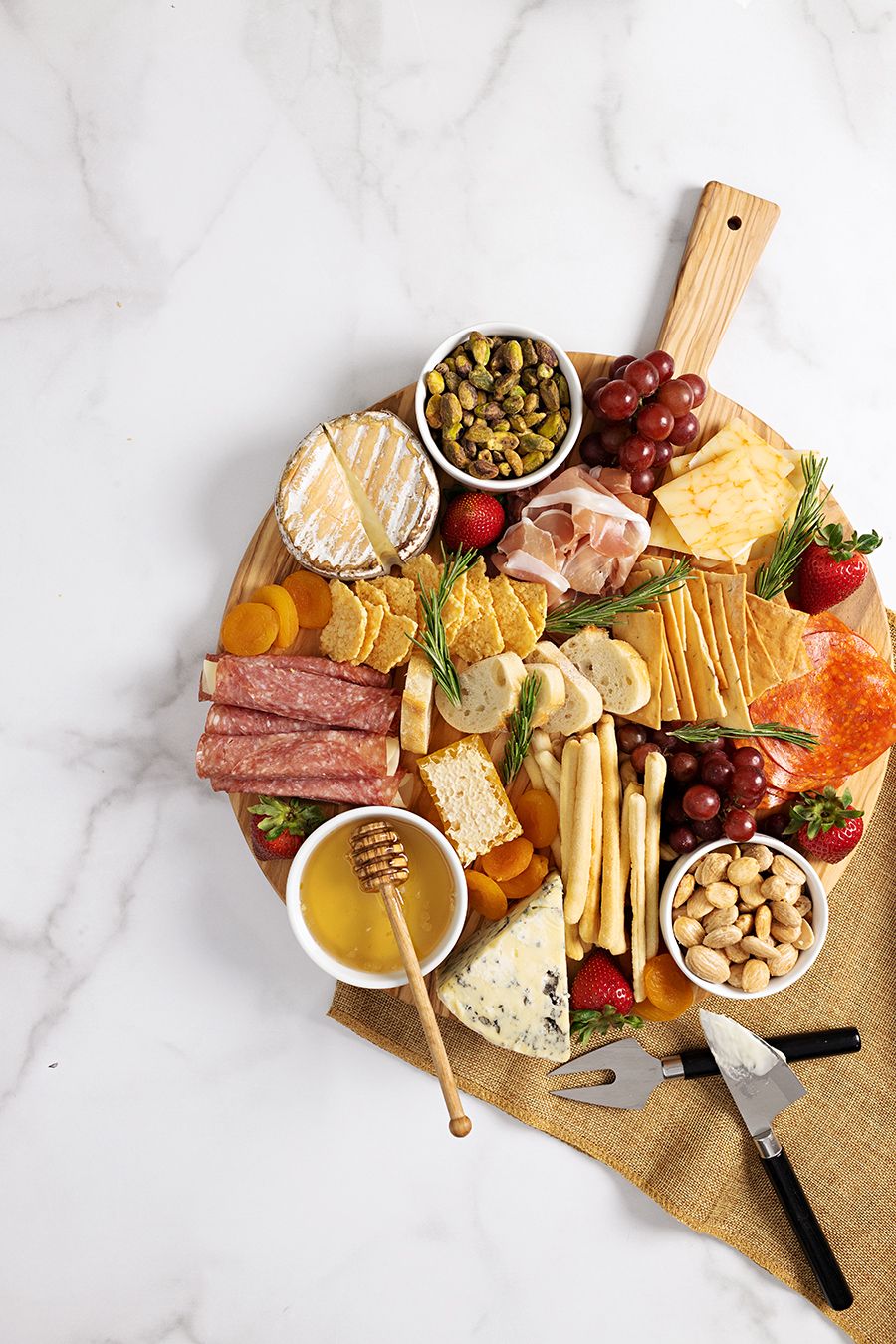 Gourmet charcuterie board with assorted cheeses, meats, fruits and nuts on marble surface.
