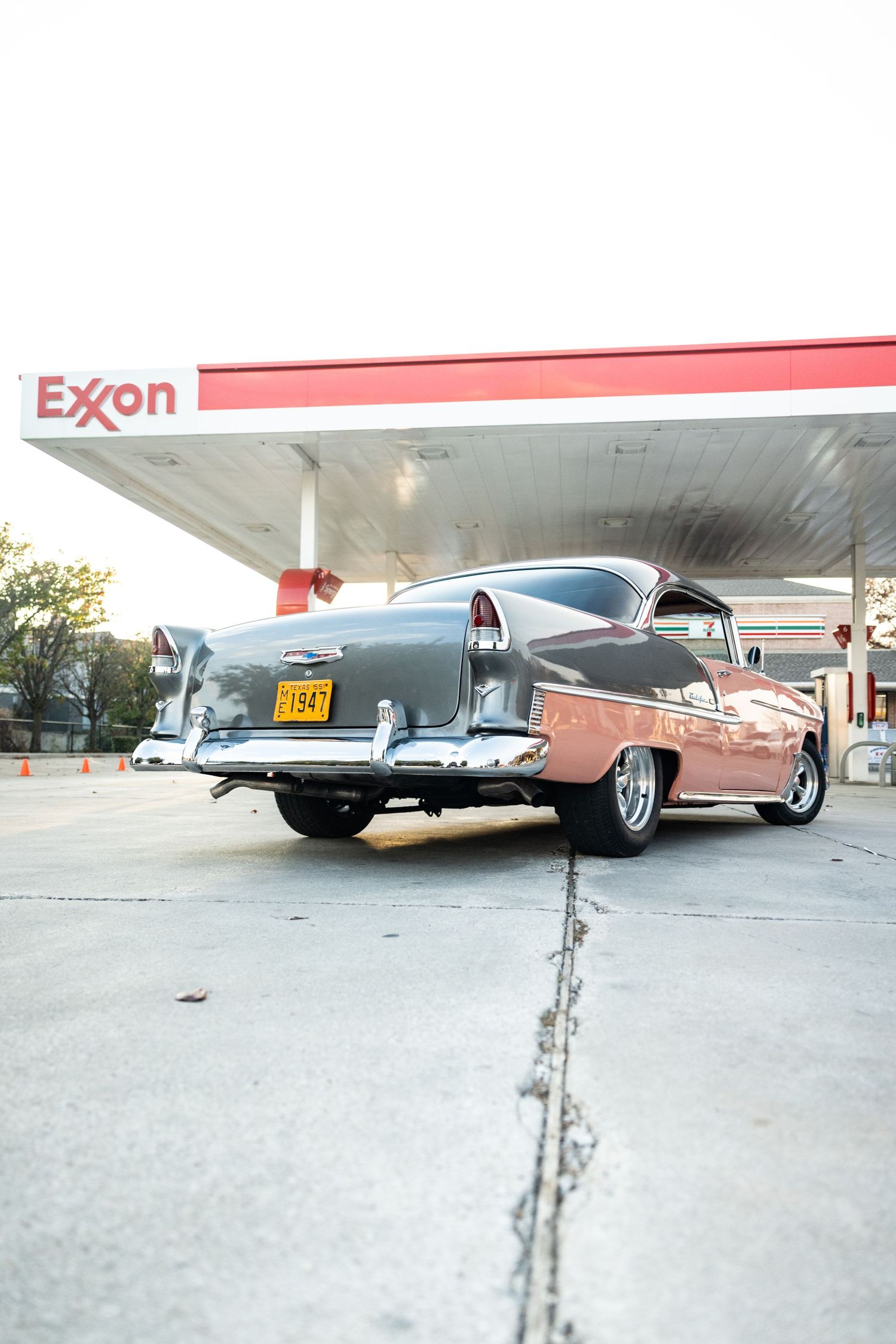 Vintage pink car parked under an Exxon gas station canopy.