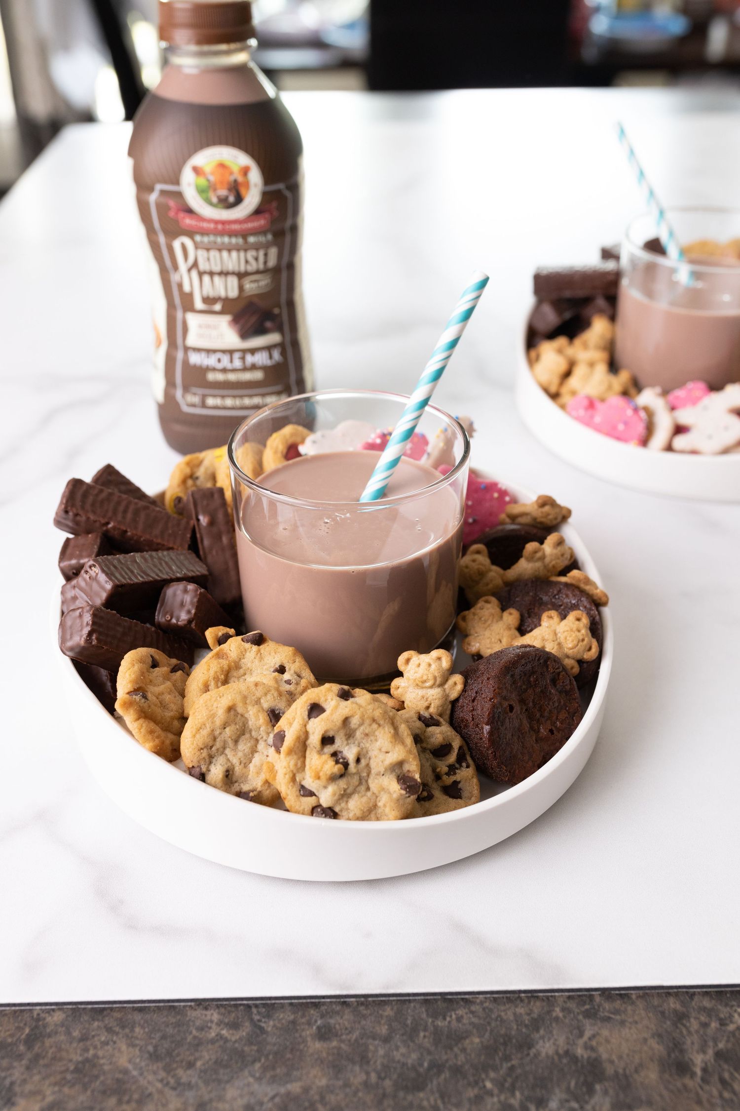Chocolate milk served with assorted cookies on white plates.