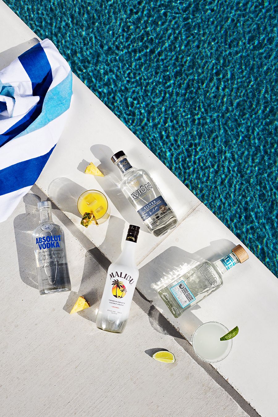 Various miniature alcohol bottles arranged on turquoise carpet with natural lighting.