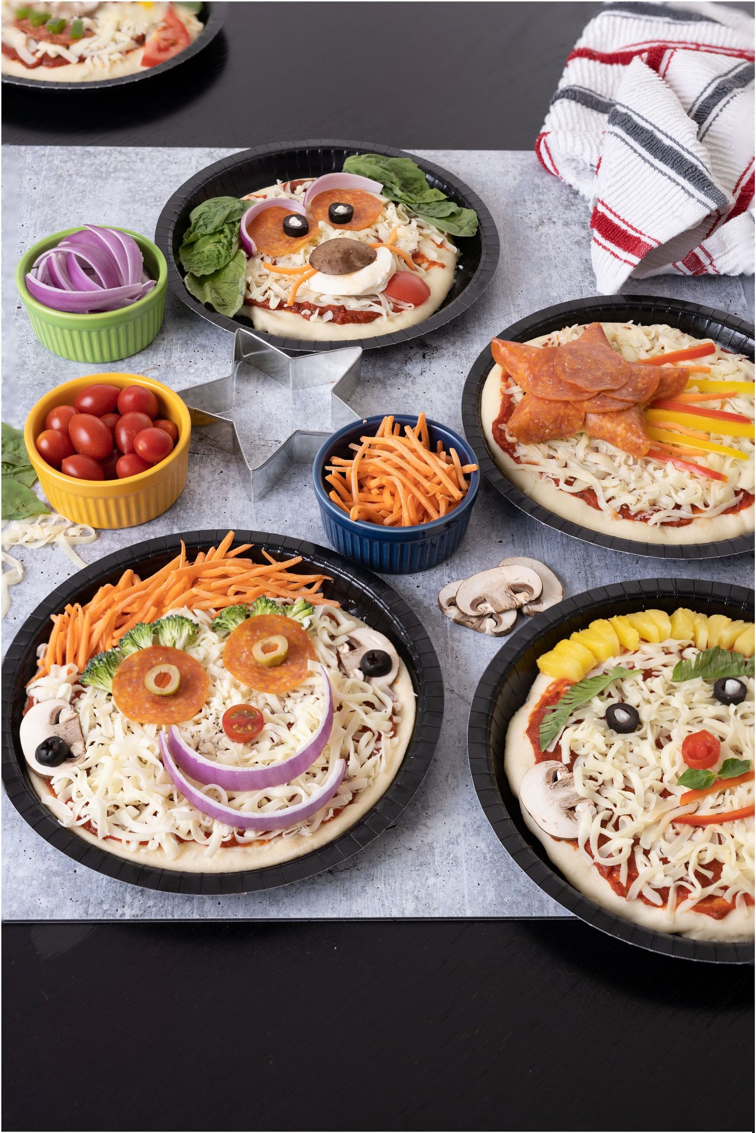 Creative pizza faces decorated with vegetables and toppings to look like smiling characters.