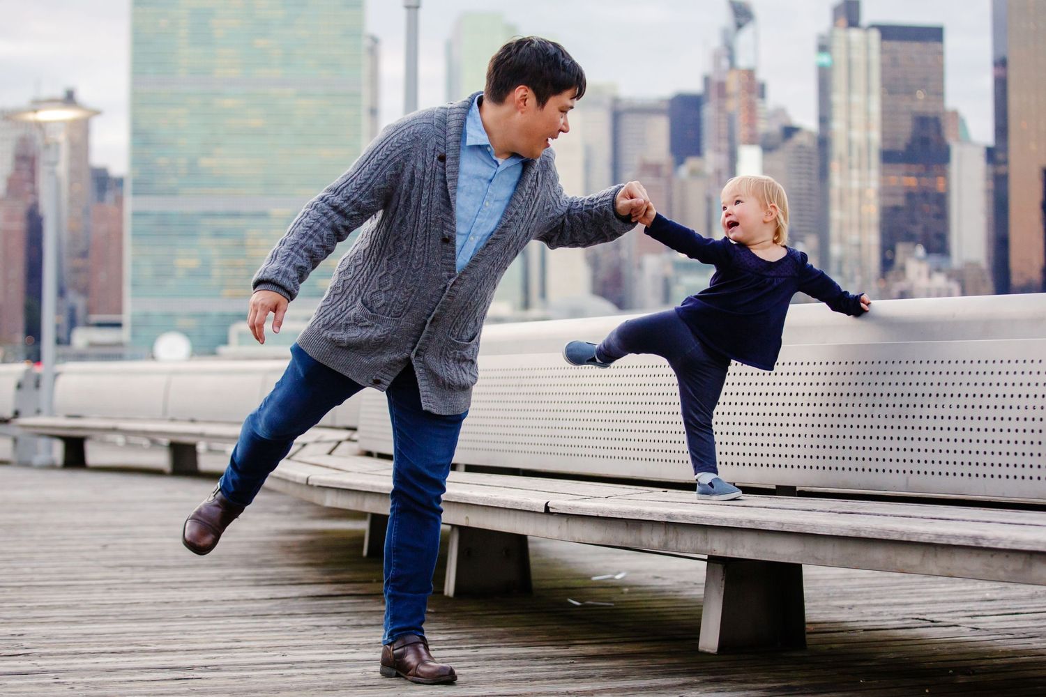 Playful scene on a pier with city skyline in background.