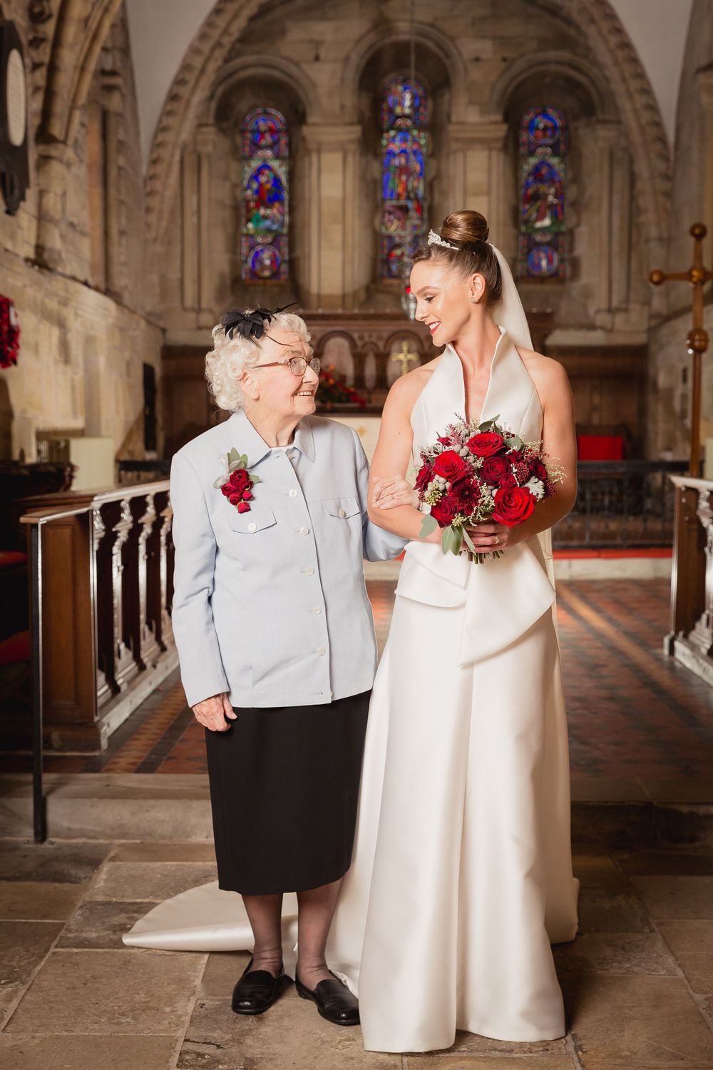 Elegant wedding photos in church aisle with stone columns and stained glass windows.