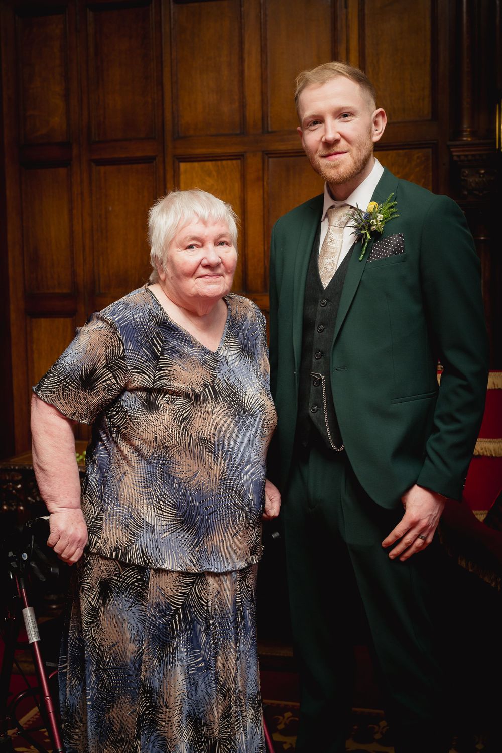 Wedding portraits in wood-paneled room with formal attire and dark green suit.