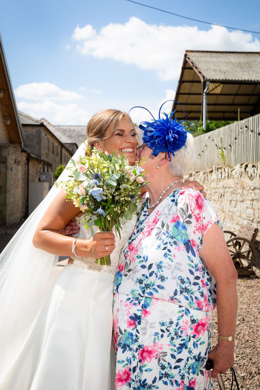A series of candid wedding photos showing guests in floral dresses and white gowns against a rustic stone wall backdrop.