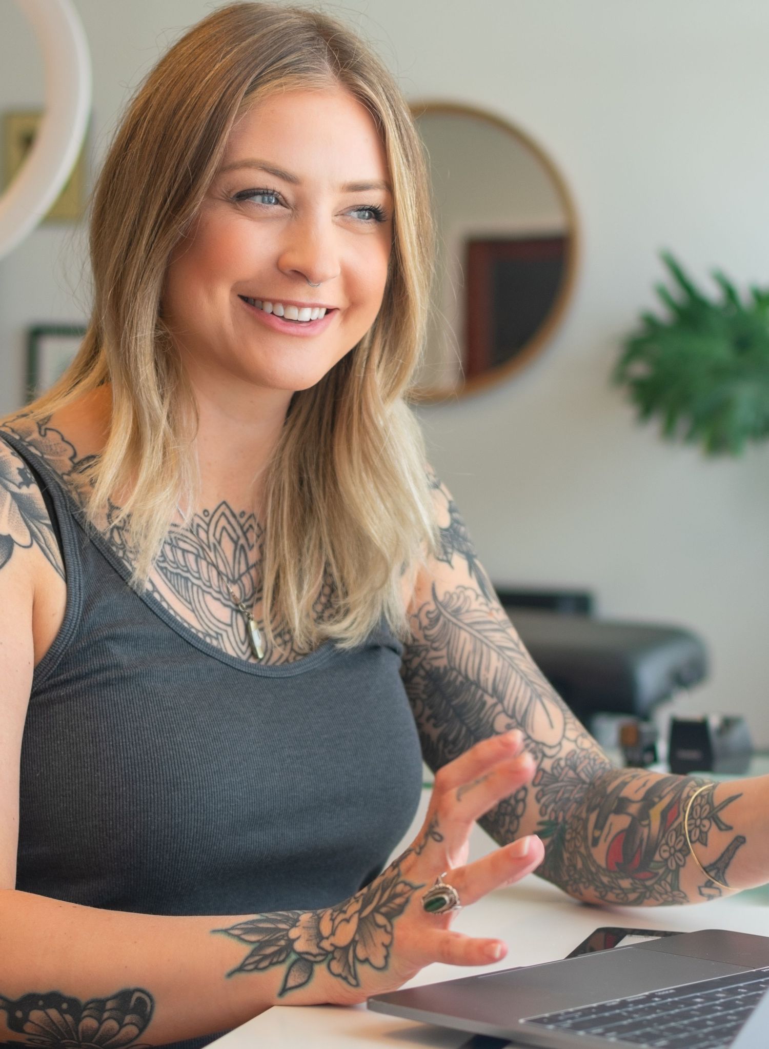 Beautiful woman sitting at a work desk with laptops open in front of her as she is smiling and looking off camera