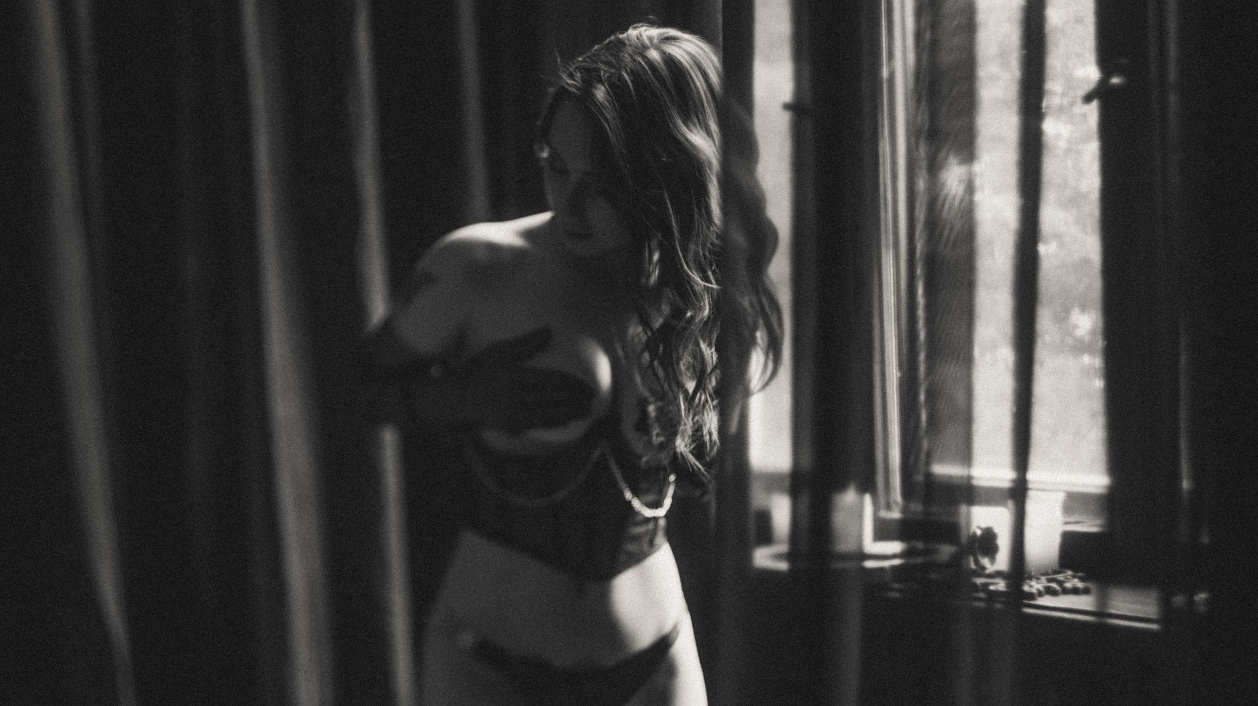 Silhouette by window in intimate portrait with dramatic lighting and shadows.