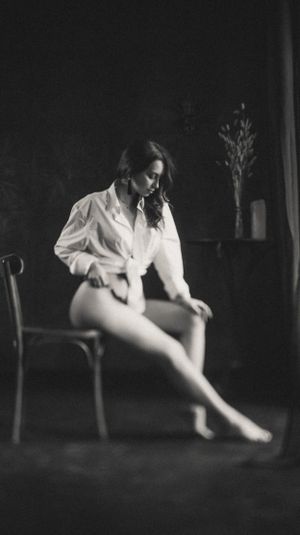 Dramatic black and white portrait series showing figure in white shirt seated in dark room.