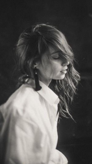 Artistic sequence of person with flowing hair in white shirt against dark background.