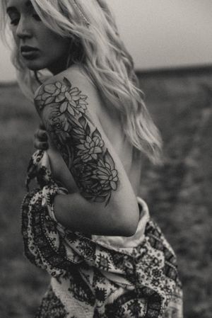 Black and white portrait showing floral tattoo details and textured clothing.