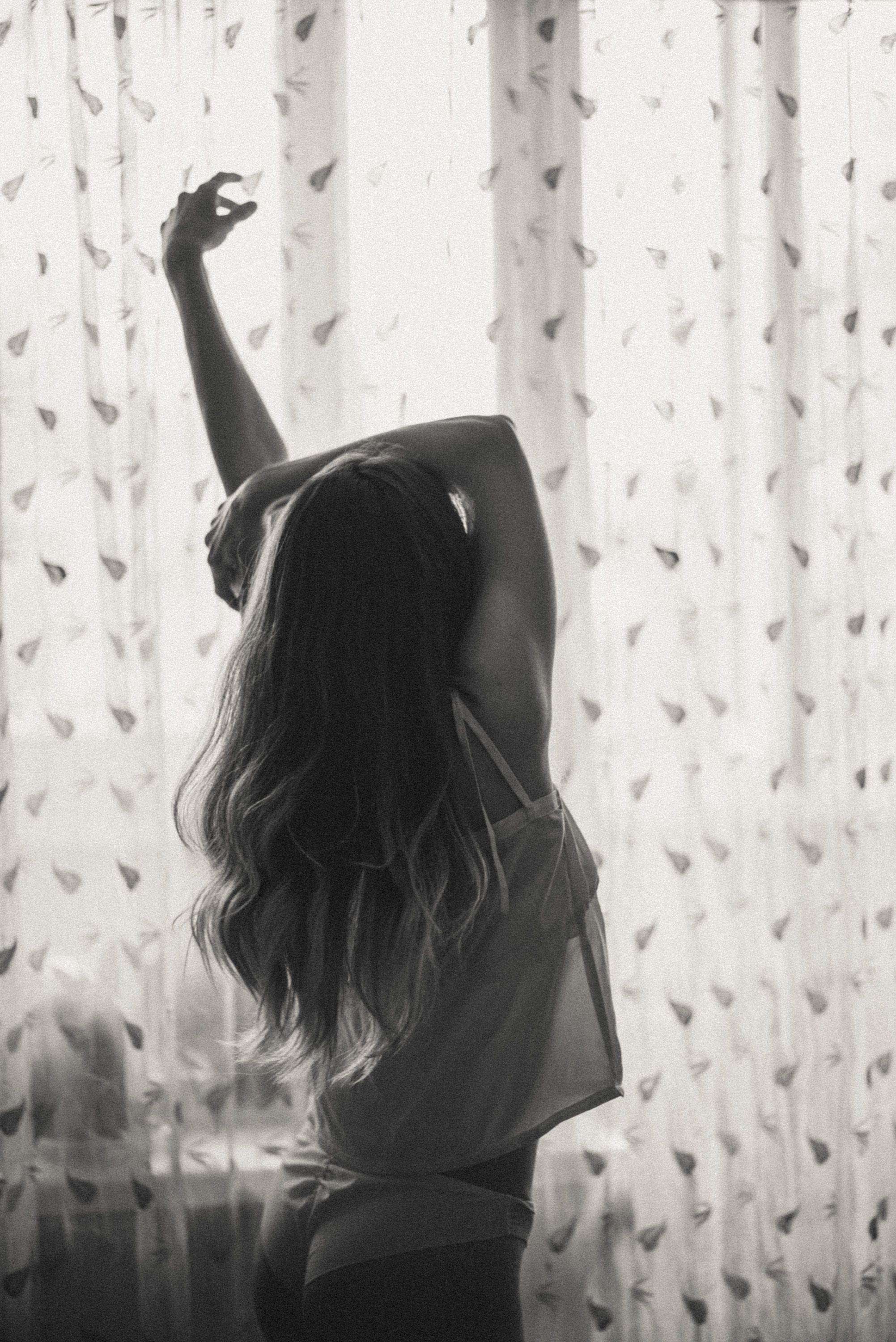 Silhouette dancing against sheer curtains in bright natural light.