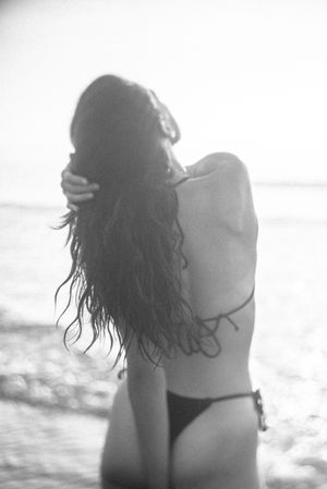Silhouette of person with flowing hair against bright background at beach.