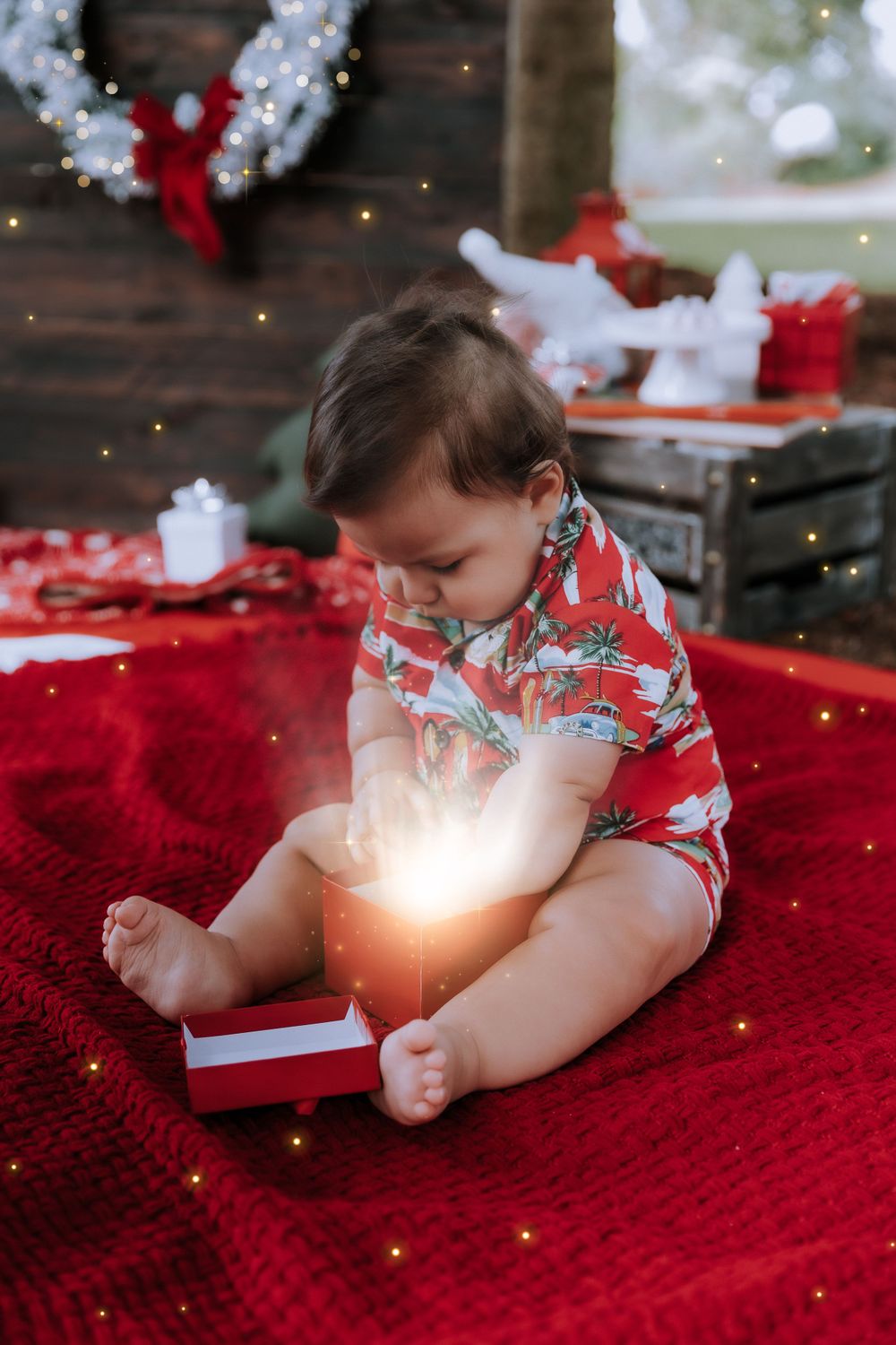 Small child laying on red blanket during Christmas photo shoot with glowing lights.