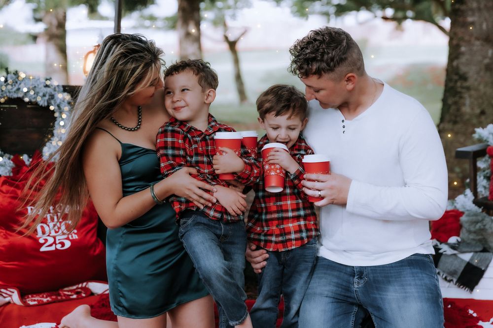 Casual family moment during Christmas photo session with matching plaid shirts and holiday decorations.