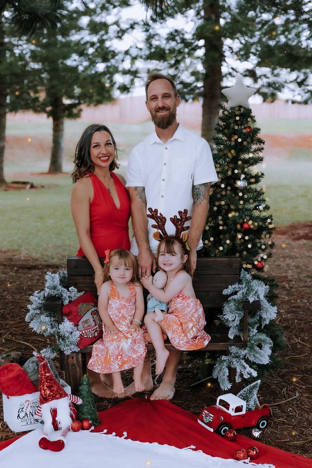 Family holiday portraits with decorated Christmas trees and red wagon props.