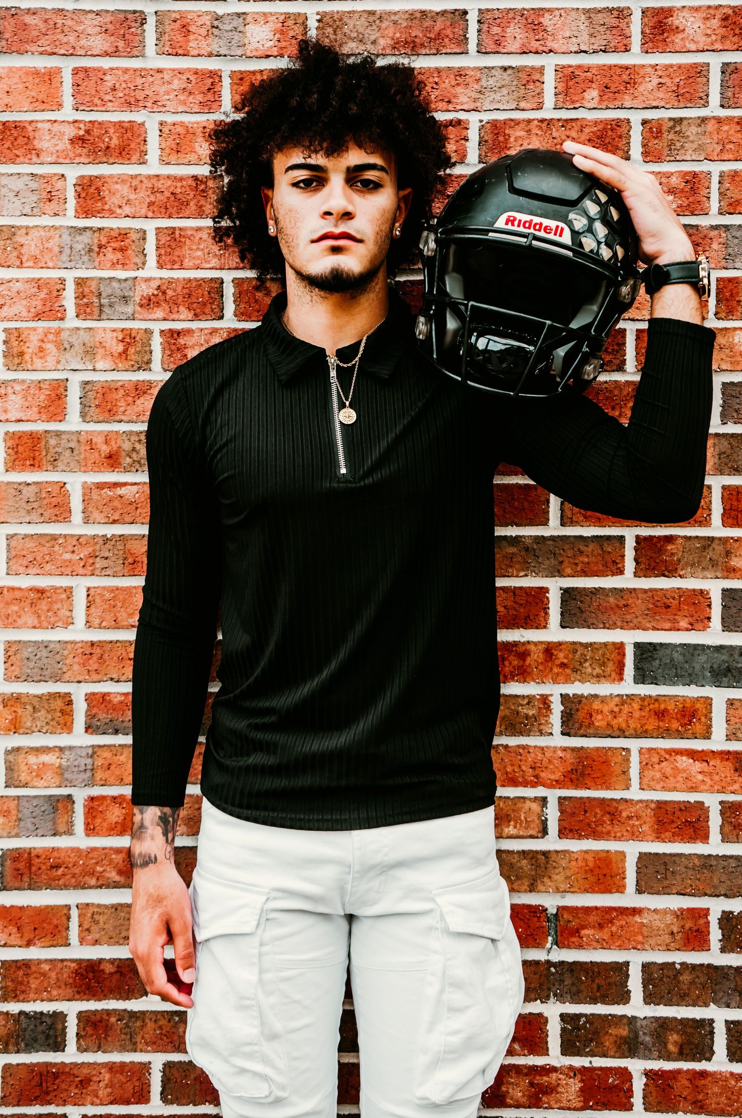 Outdoor Senior Portrait Session at University of Tampa in Tampa, FL; Senior pictures, teen holding football helmet against brick wall