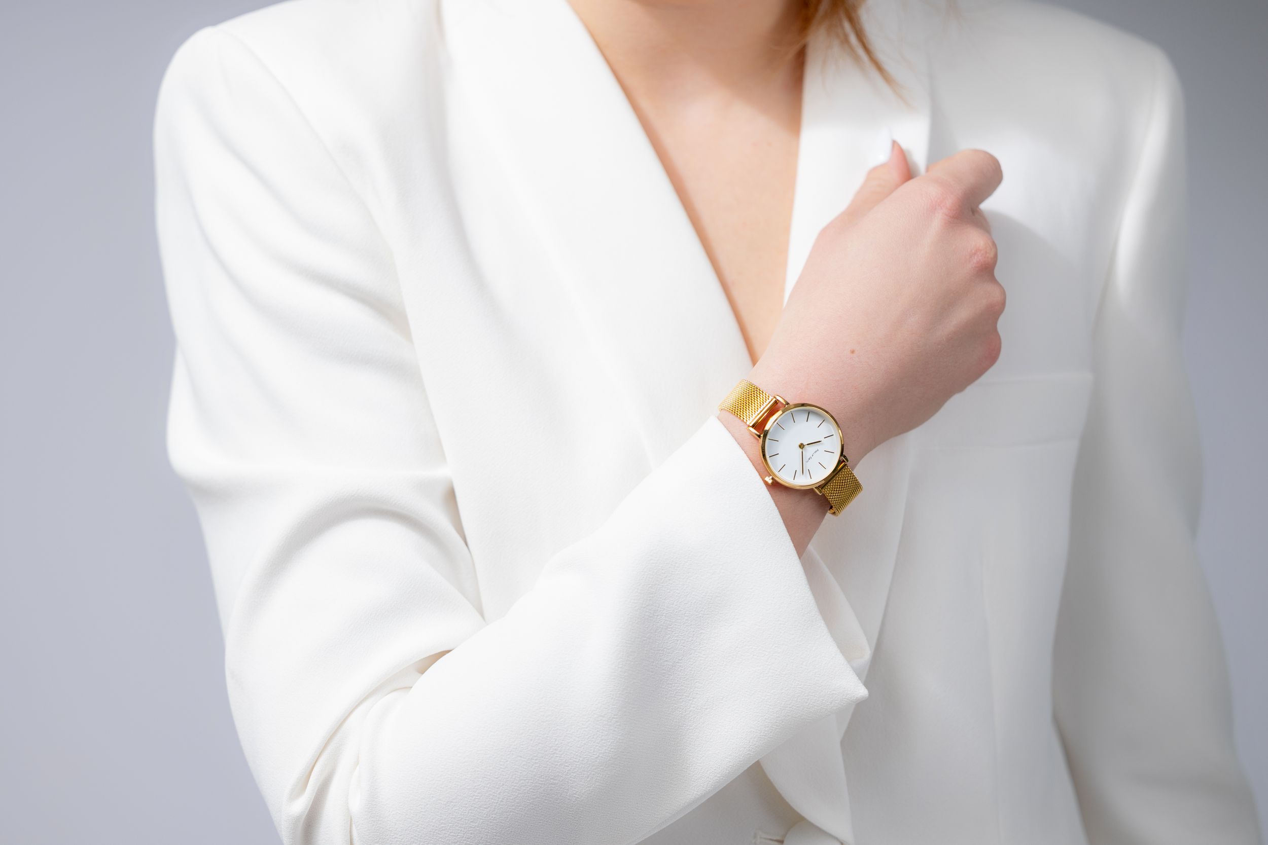 Elegant white blazer with gold watch accessory styled for fashion.