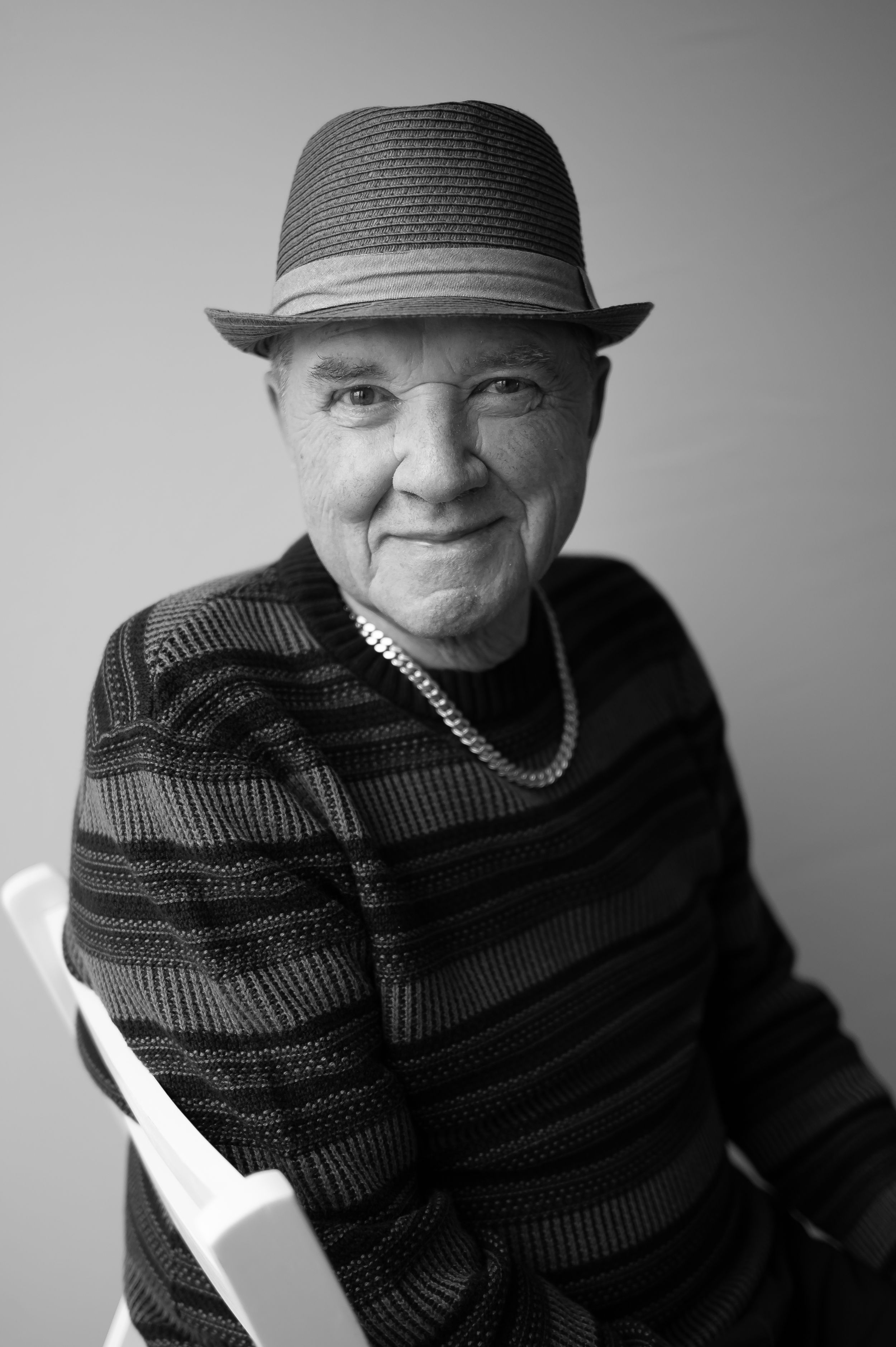 Black and white portrait of a person wearing a fedora and striped sweater.