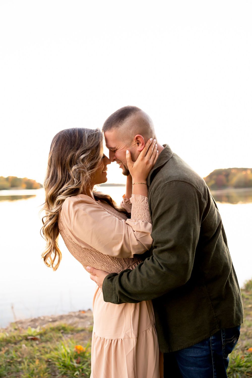 A romantic moment captured between two people by a lake at sunset.