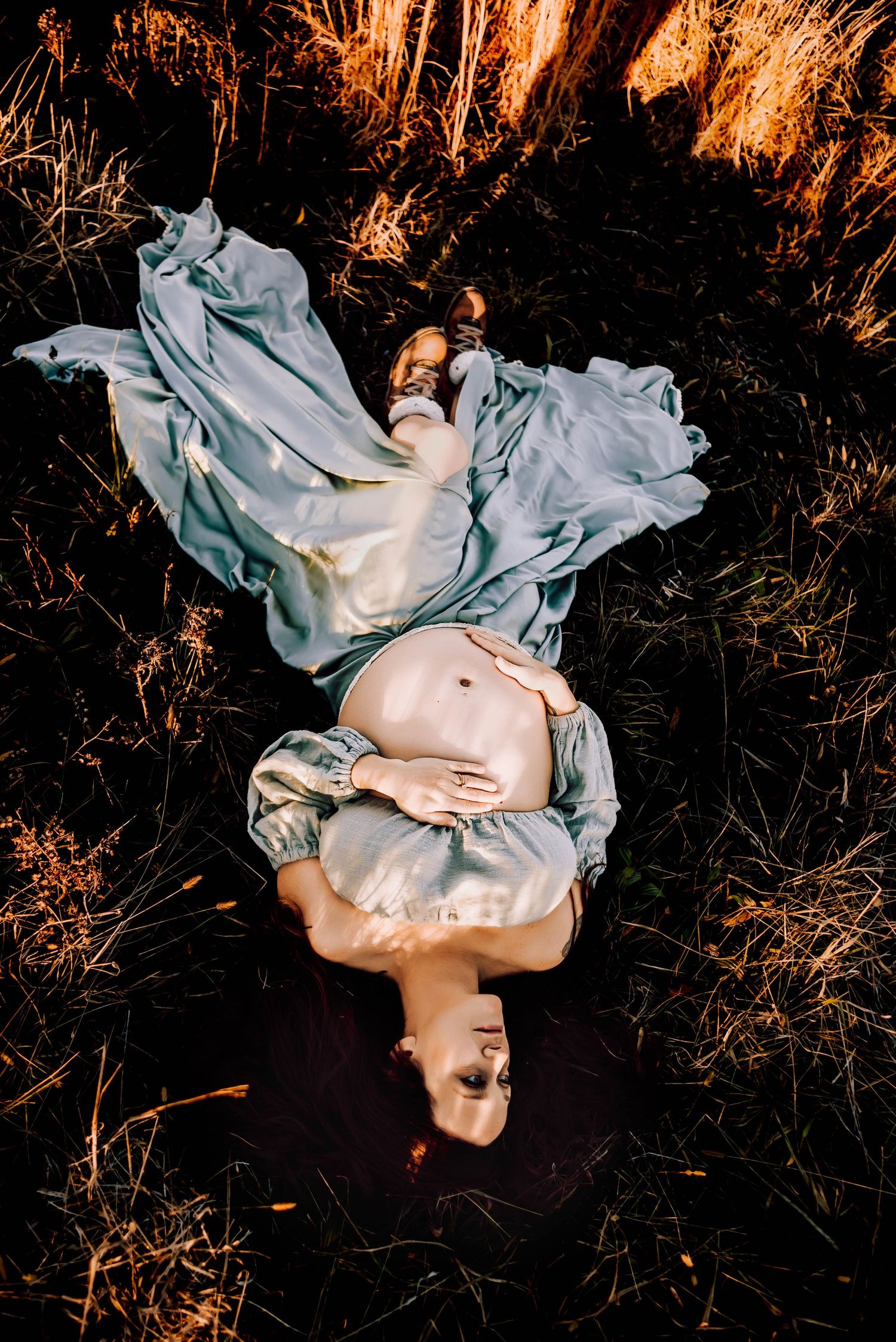 Artistic overhead shot with flowing fabric against dark grass at sunset.