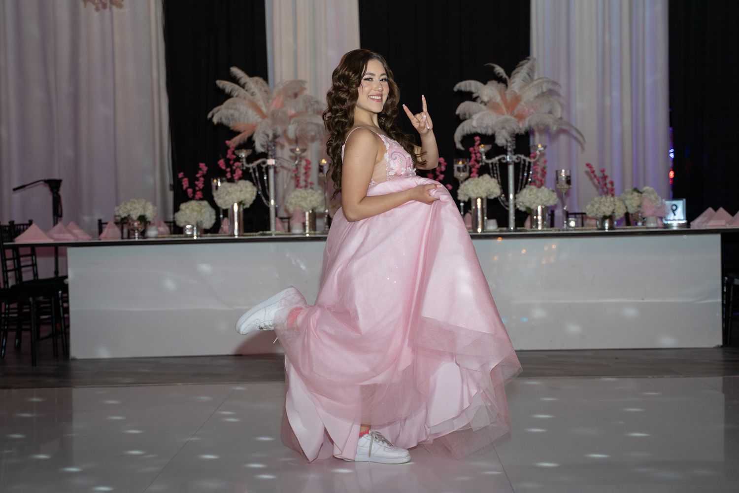 Elegant celebration in pink formal wear with decorative white backdrop.