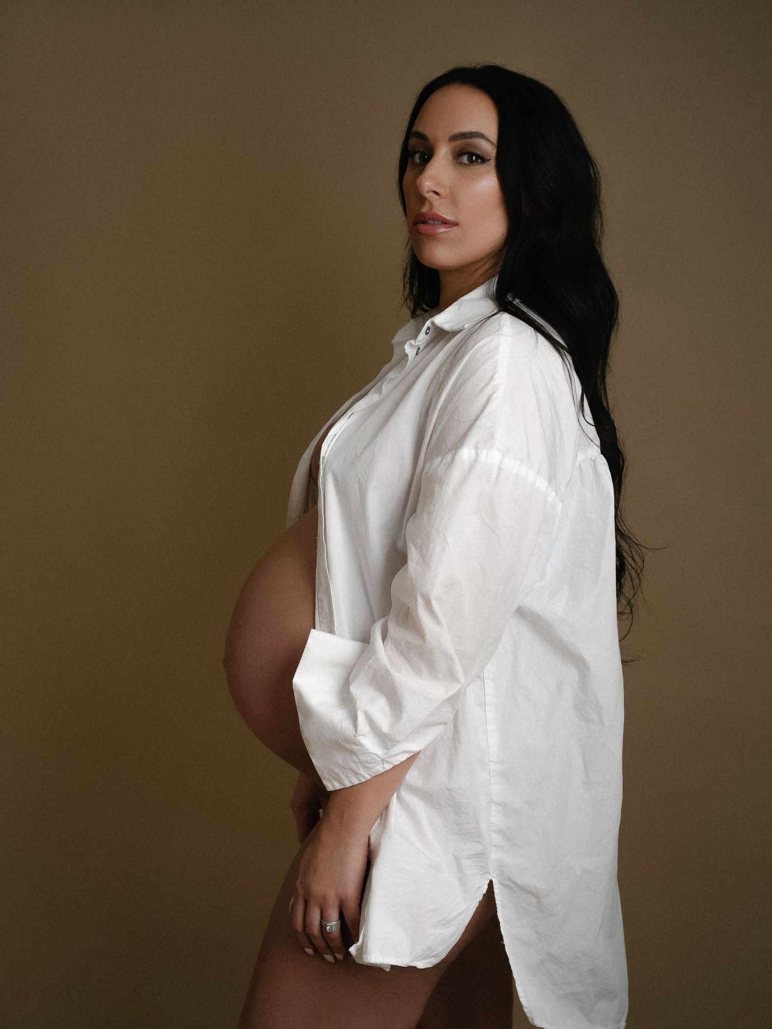 Artistic maternity photo featuring a white button-up shirt and long dark hair.