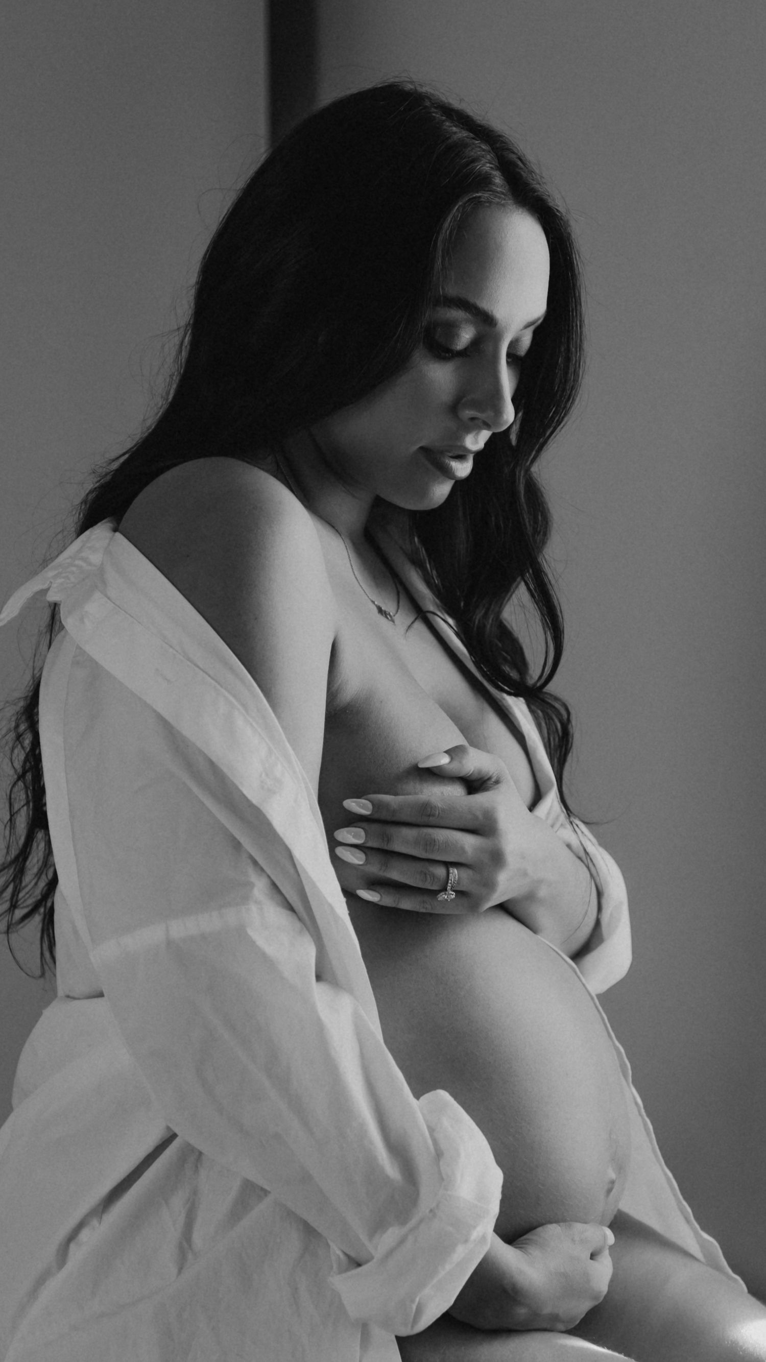 Intimate maternity portraits in monochrome featuring unbuttoned white shirt.