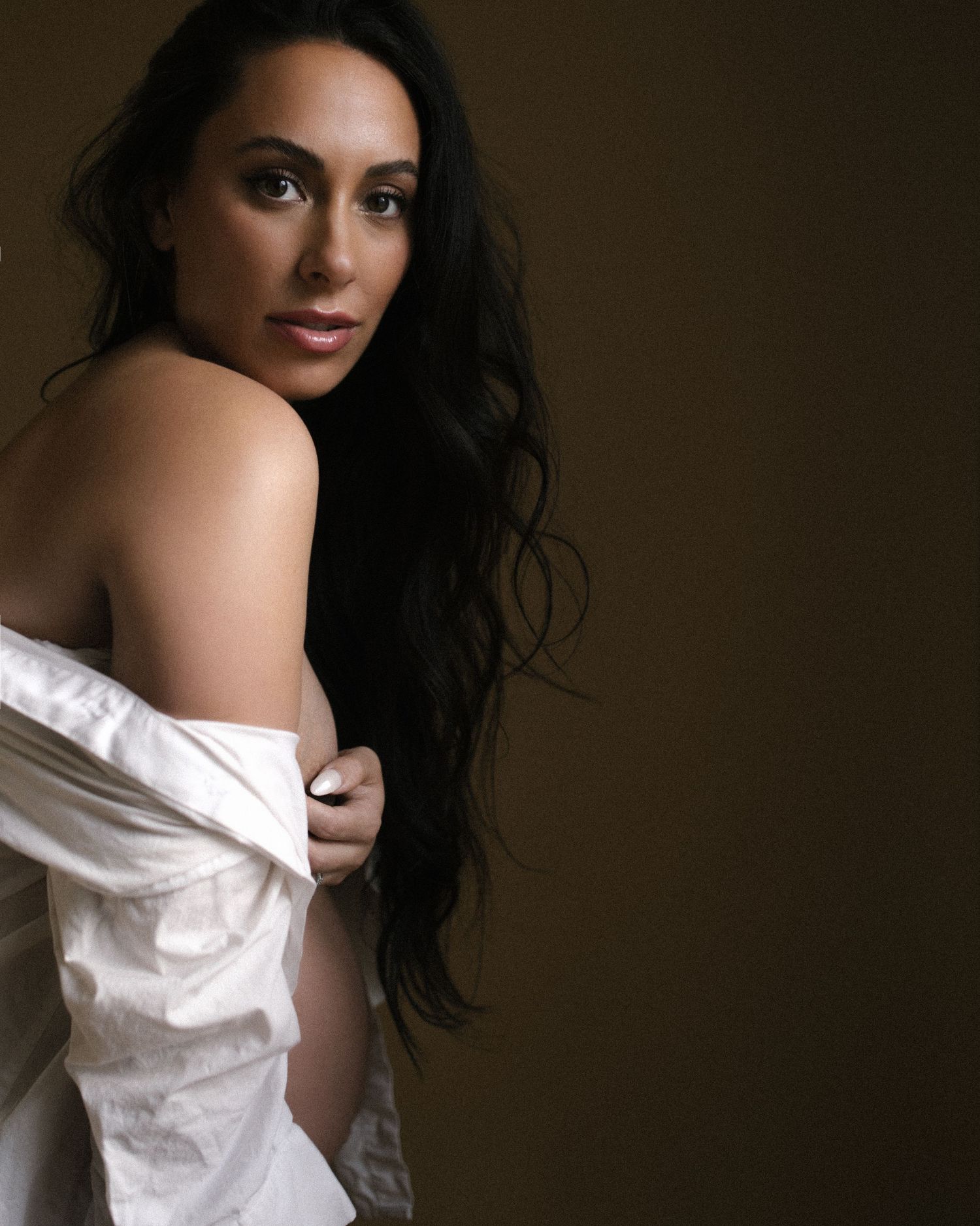 Intimate maternity portraits in warm tones with white shirt falling off shoulder.