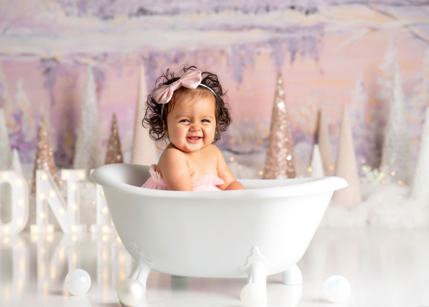 a baby smiles from a tiny bathtub