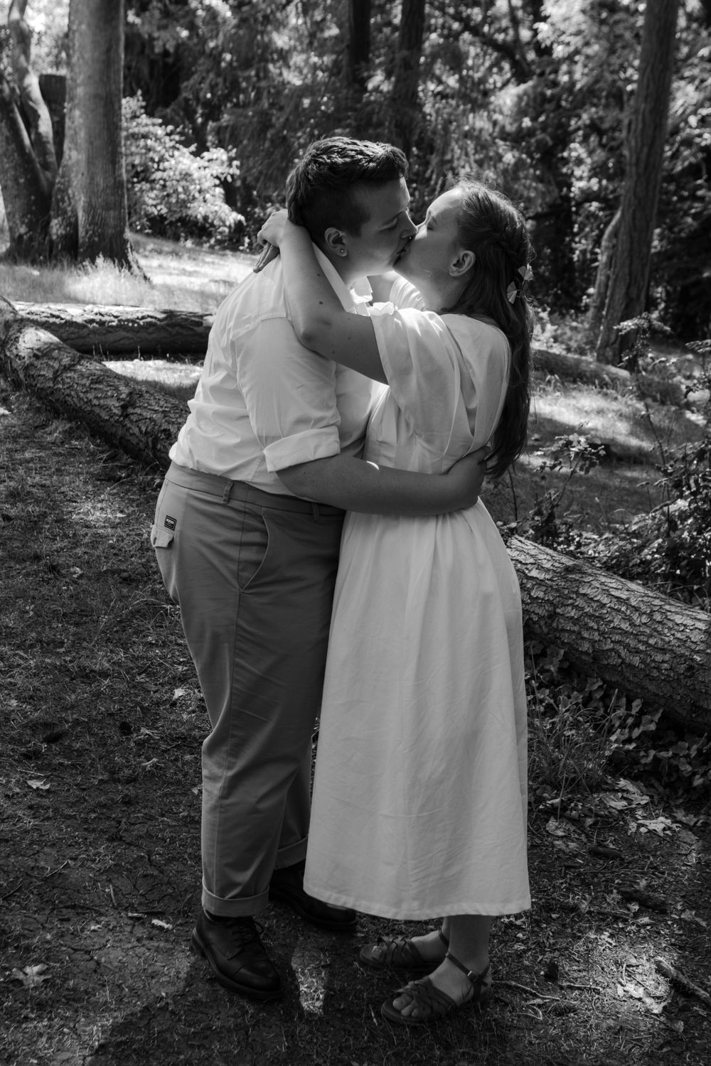 A sapphic couple kisses on their wedding day, photographed in black and white at a park in Eugene, OR