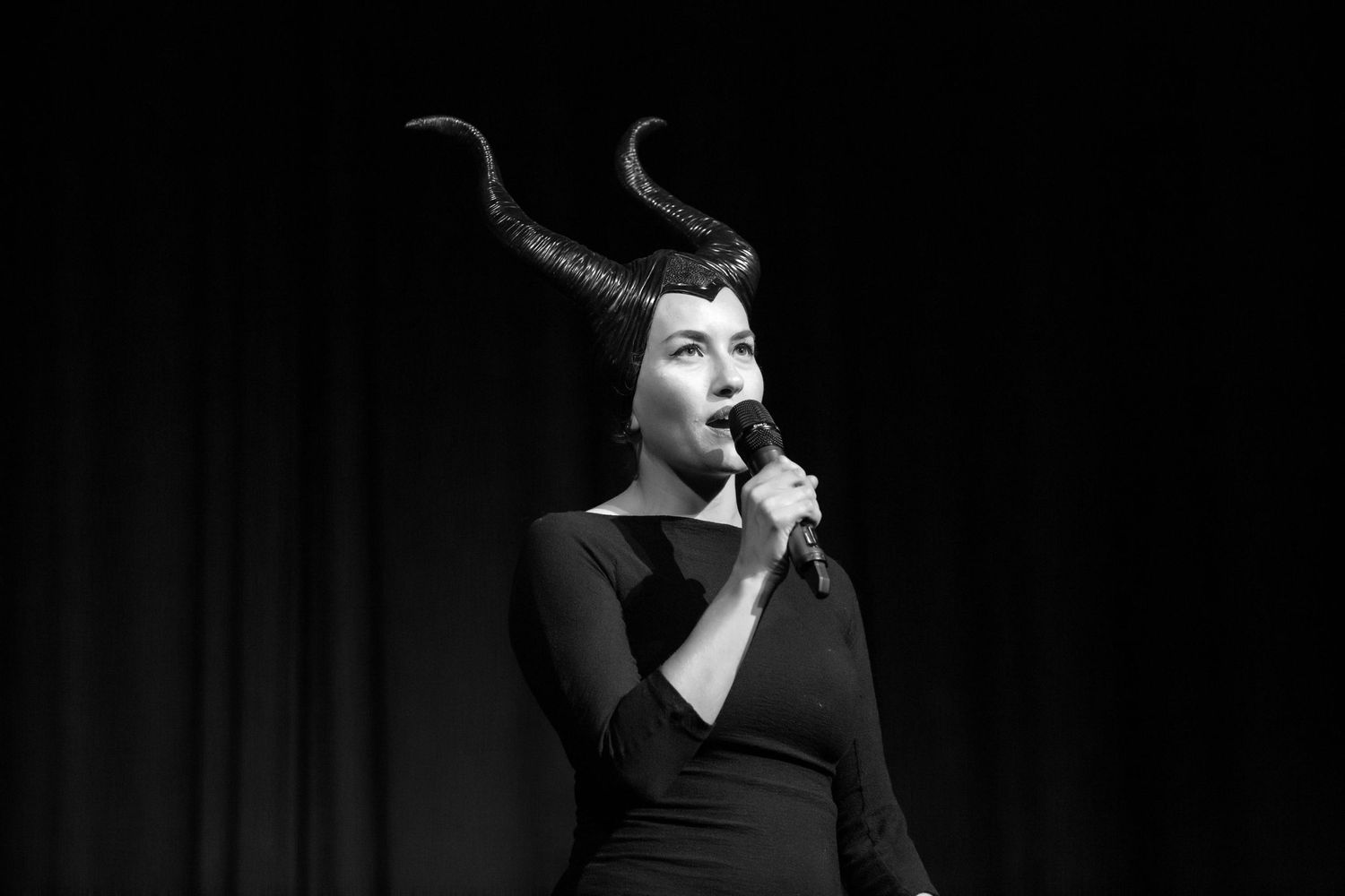 black and white event photography of a comedian on stage wearing a horned headpiece