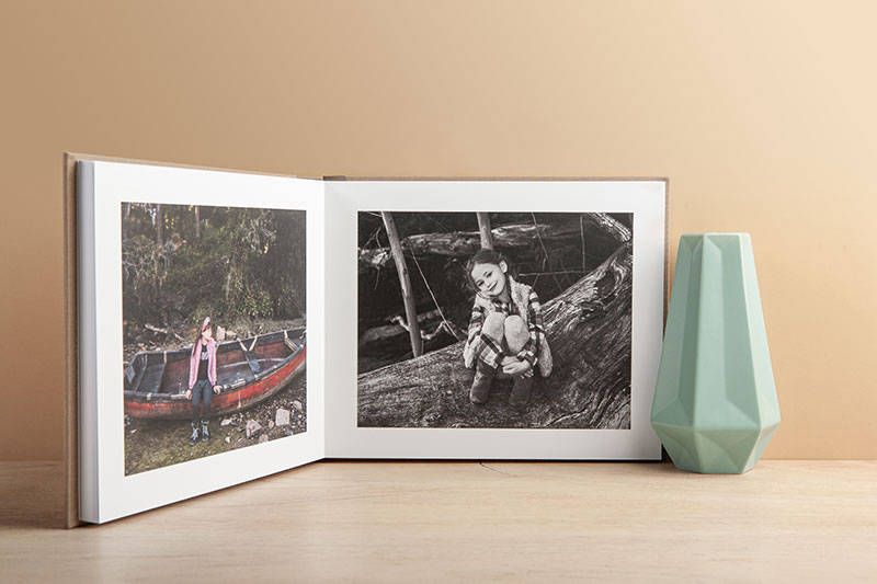 Offenes Fotoalbum mit Schwarz-Weiß-Vintage-Fotos auf Holzoberfläche mit blauer Vase.