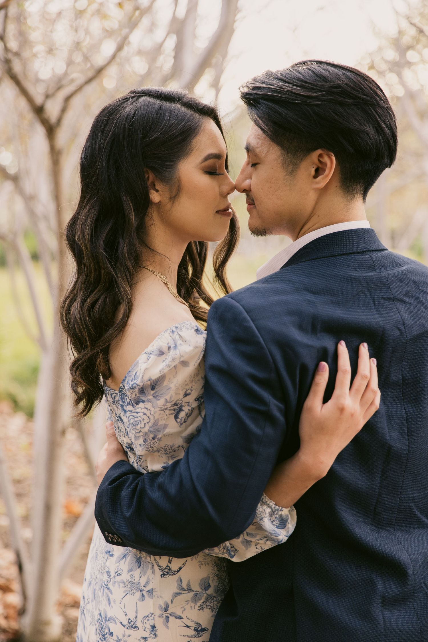 An intimate portrait of a couple in formal wear sharing a romantic moment among autumn trees.