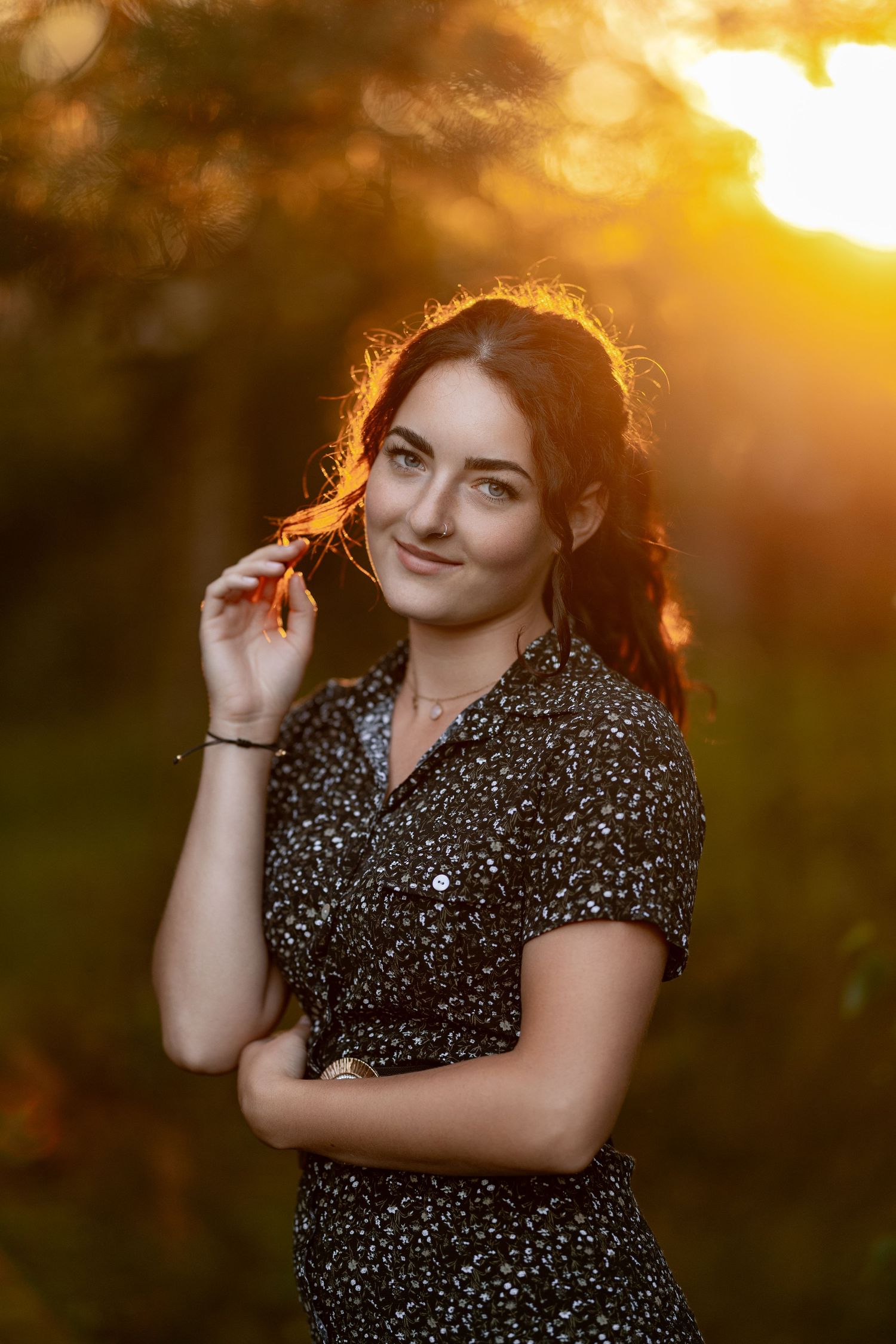 Portrait of person in floral dress at sunset with golden bokeh background.