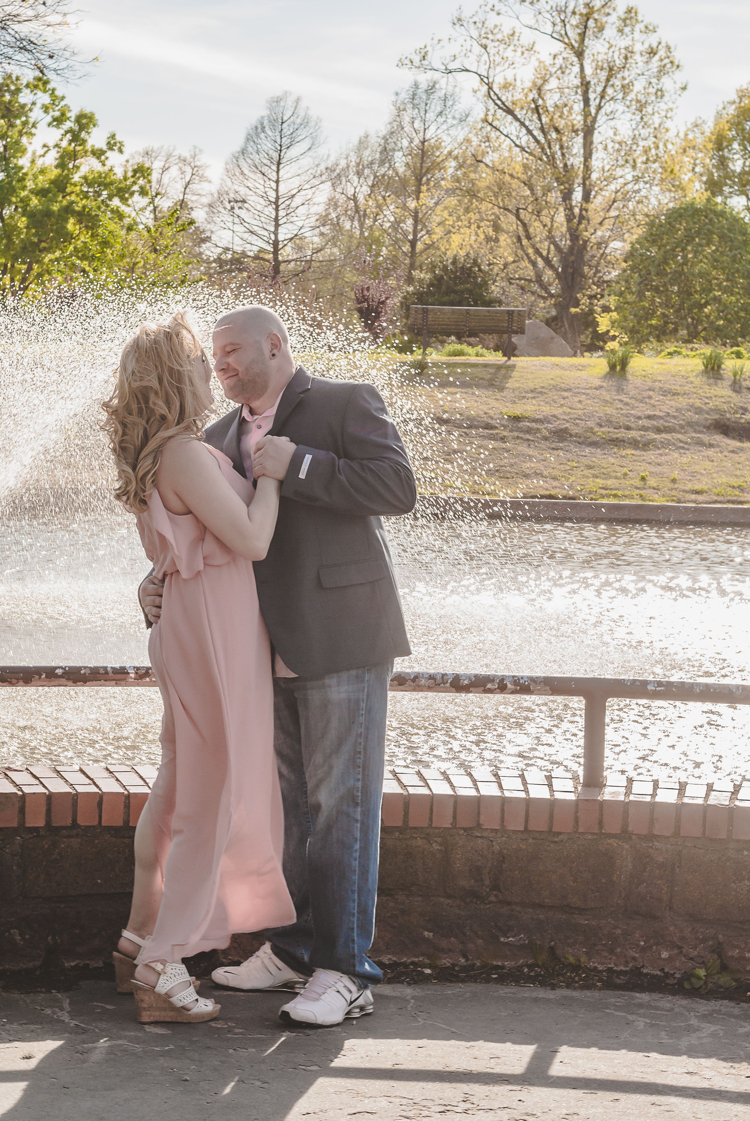a portrait of a couple in front of a water fountain dancing together