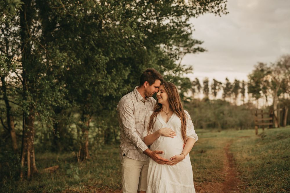 A sunset maternity portrait in a natural outdoor setting with warm lighting.