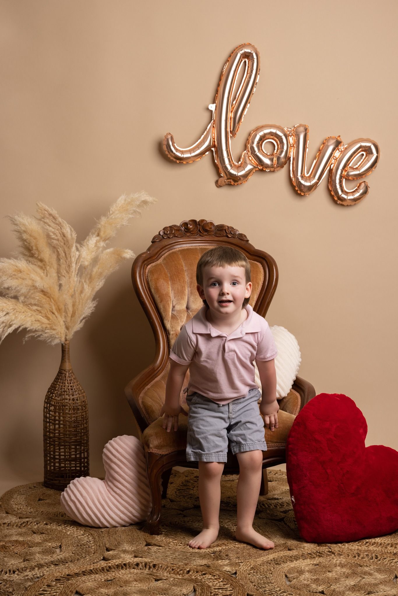 Child standing on vintage chair under rose gold love balloon with Valentine's Day decorations.