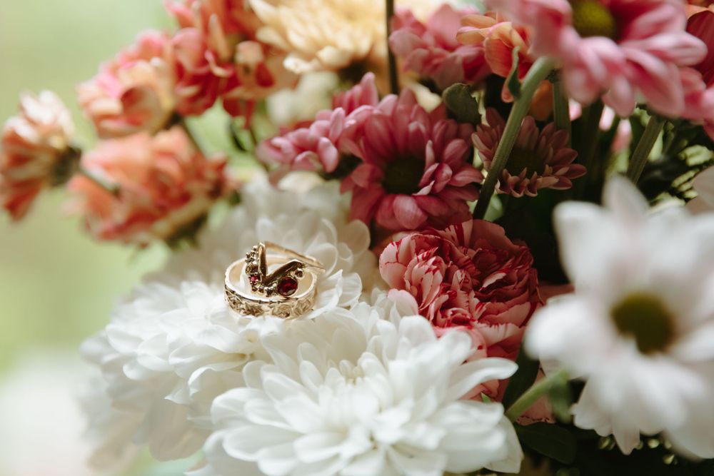 Wedding rings nestled among pink and white flowers in a romantic floral arrangement.