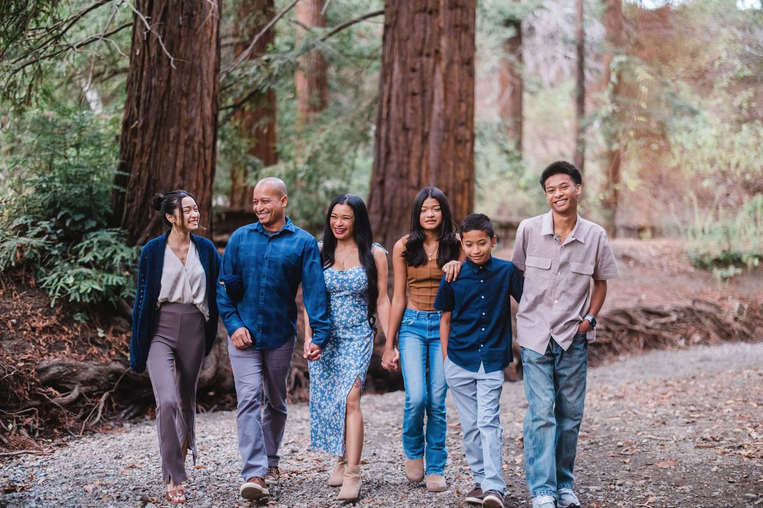 A group walks together on a trail through a majestic redwood forest.