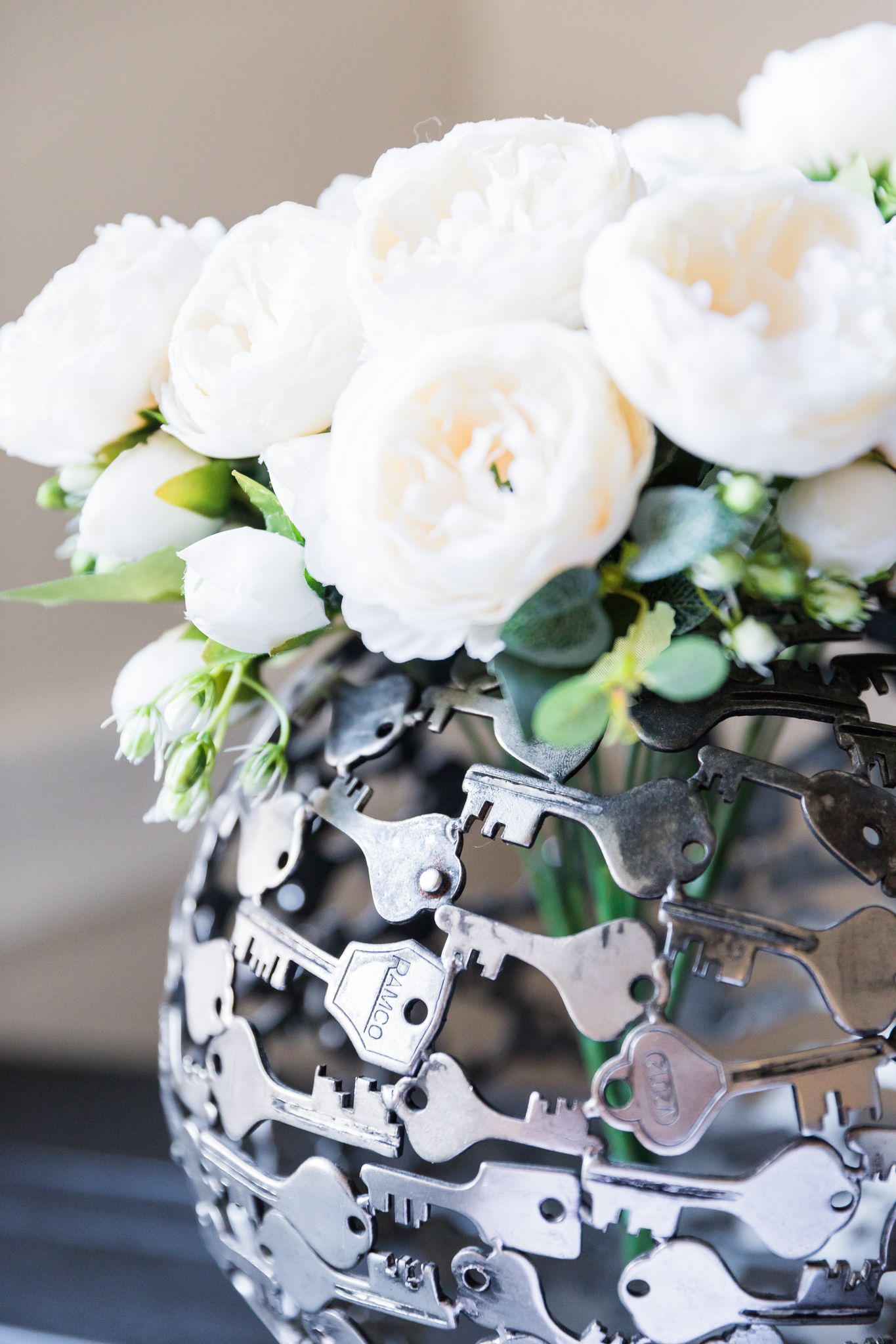 White roses in vase made of silver keys